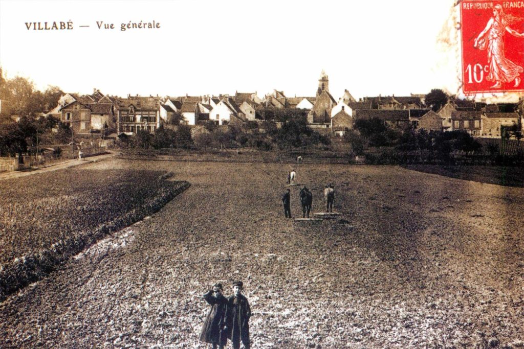 Carte postale : Vue de Villabé depuis la gare au début du XX° siècle, avant la construction de la cité Darblay dont les immeubles seront bâtis de part et d'autre de la parcelle vide